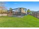 Expansive backyard featuring green lawn, a screened-in pool area, and a wooden fence for privacy at 1920 E Idlewild Ave, Tampa, FL 33610