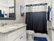 Cozy bathroom with vanity, mirror, and a shower behind a dark shower curtain at 1920 E Idlewild Ave, Tampa, FL 33610