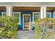 Charming front porch with blue siding, a decorative front door, and landscaping around the home's entrance at 1920 E Idlewild Ave, Tampa, FL 33610