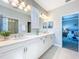 Bright bathroom with double vanity, marble countertops, and a glass-enclosed shower with views to the bedroom at 29197 Perilli Pl, Wesley Chapel, FL 33543