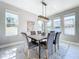 Dining room with ample natural light, modern light fixture, seating for six, and a gray area rug at 29197 Perilli Pl, Wesley Chapel, FL 33543