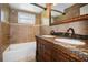 Bathroom featuring a double sink vanity with decorative mirror, tile walls, and a bathtub with shower at 3087 Duane Ave, Oldsmar, FL 34677