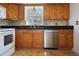 Close-up of oak kitchen cabinets with stainless steel dishwasher, black countertop, and tile flooring at 3087 Duane Ave, Oldsmar, FL 34677