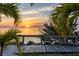 Beautiful sunset view through palm trees with dock extending into the tranquil waters at 3244 Mangrove Point Dr, Ruskin, FL 33570