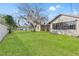 Expansive backyard with lush green grass, mature trees, and a view of the home's exterior at 4472 Bayridge Ct, Spring Hill, FL 34606