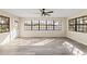 Bright living room featuring large windows, gray wood flooring, and a modern ceiling fan at 4472 Bayridge Ct, Spring Hill, FL 34606