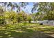 Large backyard with ample space, mature trees, and a storage shed on the side at 620 Scotland St, Dunedin, FL 34698