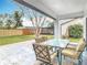 Covered patio showing a glass-topped outdoor dining set with seating for six overlooking the spacious backyard at 7800 Willow Brook Ct, Hudson, FL 34667