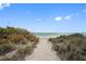 Pathway to a pristine beach with clear skies and gentle waves at 860 Virginia St # 303, Dunedin, FL 34698