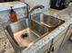 Close up of double stainless steel kitchen sink with granite-look countertop at 860 Virginia St # 303, Dunedin, FL 34698