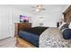 This primary suite features a decorative bed frame, ceiling fan, television and ensuite bathroom at 10340 Ventura Dr, Spring Hill, FL 34608