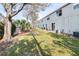 A view of the back of the townhome with grassy backyard space, air conditioning units and sliding glass doors at 12704 Country Brook Ln, Tampa, FL 33625