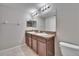 Bathroom featuring dual sinks, granite countertops, wood cabinets, and large mirror at 12973 Dream Catcher Way, Riverview, FL 33579