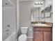 Bathroom featuring a granite countertop, wood cabinets, a mirror, and a shower-tub combo at 12973 Dream Catcher Way, Riverview, FL 33579