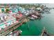 Picturesque aerial view of a waterfront dock featuring charming shops, fishing boats, and turquoise waters at 13235 Gulf Blvd # 306, Madeira Beach, FL 33708