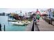 Vibrant boardwalk scene with shops, boats, and people enjoying a sunny day by the water at 13235 Gulf Blvd # 306, Madeira Beach, FL 33708
