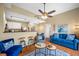 Bright living room featuring a blue sofa set, ceiling fan and an open view of the kitchen and dining area at 13235 Gulf Blvd # 306, Madeira Beach, FL 33708