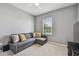 Cozy bedroom featuring a comfortable gray sofa, a bright window, and neutral carpet flooring at 1896 Tallulah Ter, Wesley Chapel, FL 33543