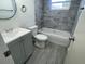 Bright bathroom features a modern vanity with cabinet storage, toilet, and tub with marbled-tile surround at 2036 Melody Dr, Holiday, FL 34691
