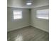Bedroom with wood-look flooring and two windows with blinds at 2036 Melody Dr, Holiday, FL 34691