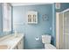 Compact bathroom with blue walls, a vanity with a white countertop, and a shower with glass doors at 36852 Kimela Ave, Zephyrhills, FL 33542