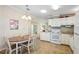 Kitchen with white cabinetry, appliances, and a dining area featuring a round wooden table with four chairs at 36852 Kimela Ave, Zephyrhills, FL 33542