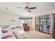 Bright living room featuring neutral carpet, ceiling fan, comfortable seating, and sliding glass doors to the sunroom at 36852 Kimela Ave, Zephyrhills, FL 33542