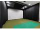 Modern golf simulator room with dark curtains, golf mat and projector screen for immersive play at 5120 Marina Way # 6603, Tampa, FL 33611