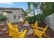 Backyard area with a fire pit surrounded by yellow Adirondack chairs and lush tropical landscaping at 1235 Willowick Cir, Safety Harbor, FL 34695