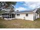 Back exterior view of a home with a screened-in patio, solar panels, and landscaped yard at 1409 Coachlight Way, Dunedin, FL 34698