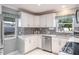 Bright kitchen featuring white cabinetry, stainless steel appliances, and a mosaic backsplash at 1409 Coachlight Way, Dunedin, FL 34698