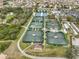 Aerial view of multiple tennis courts with green surfaces, surrounded by trees and community buildings at 1509 Blackstone Cir, Sun City Center, FL 33573