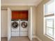 Laundry room with front-load washer and dryer, wooden cabinets, and window with blinds at 2105 Clover Hill Rd, Palm Harbor, FL 34683