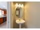 Stylish half bathroom with a pedestal sink, decorative lighting, and neutral paint at 2105 Clover Hill Rd, Palm Harbor, FL 34683