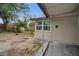 View of backyard with exterior access door, small patio area, some greenery, trees, and room to landscape at 306 S Highland Ave, Clearwater, FL 33755