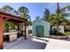 Outdoor kitchen area featuring built-in BBQ, outdoor shed and well maintained landscape at 3089 Enisglen Dr, Palm Harbor, FL 34683