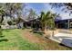 Landscaped backyard with retaining wall, view of home, lanai and a white privacy fence at 3089 Enisglen Dr, Palm Harbor, FL 34683