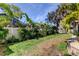 Well maintained lawn with lush tropical landscaping, fencing, and a glimpse of the screened lanai at 3089 Enisglen Dr, Palm Harbor, FL 34683