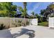 Backyard view features a white privacy fence and tropical landscaping and a manicured lawn at 3089 Enisglen Dr, Palm Harbor, FL 34683