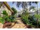 View of brick paver path in backyard surrounded by lush, mature landscaping at 3089 Enisglen Dr, Palm Harbor, FL 34683