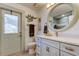 Bathroom featuring a vanity with a white countertop, a round mirror, and decorative wall art at 3089 Enisglen Dr, Palm Harbor, FL 34683