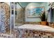 Bathroom with jacuzzi tub, mosaic tile surround, glass shower door, and decorative wall art at 3089 Enisglen Dr, Palm Harbor, FL 34683