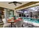 Covered patio dining area with a view of the screened-in pool and outdoor lounge area, perfect for entertaining at 3089 Enisglen Dr, Palm Harbor, FL 34683