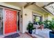 Inviting front porch with a bright red door and cozy seating area at 3089 Enisglen Dr, Palm Harbor, FL 34683
