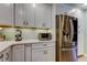 Kitchen with stainless steel fridge, light gray cabinets, white counters and undermount lighting at 3089 Enisglen Dr, Palm Harbor, FL 34683