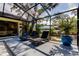 Outdoor screened patio with two lounge chairs, tropical landscaping, and comfortable seating at 3089 Enisglen Dr, Palm Harbor, FL 34683