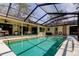 Relaxing pool area featuring clear blue water, a screened enclosure, and convenient access to the covered patio at 3089 Enisglen Dr, Palm Harbor, FL 34683
