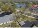 Aerial view of the property showcasing the pond, mature trees, and nearby building with ample parking at 3401 Killdeer Pl, Palm Harbor, FL 34685