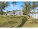Exterior view of the home featuring a well-manicured lawn, mature trees, and privacy fence at 3401 Killdeer Pl, Palm Harbor, FL 34685