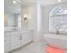 Elegant bathroom features a vanity with marble countertop and a freestanding tub under an arched window at 4610 W Browning Ave, Tampa, FL 33629